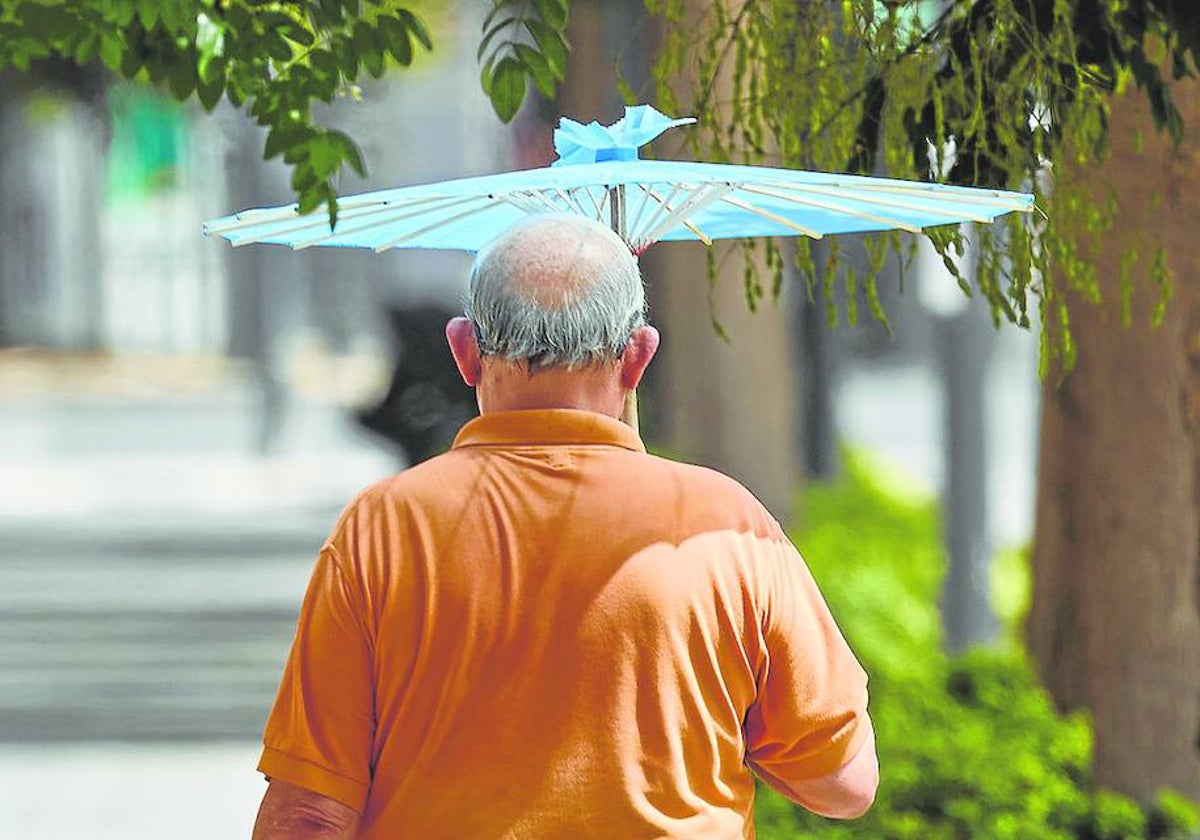 Un hombre se protege del sol con un paraguas.