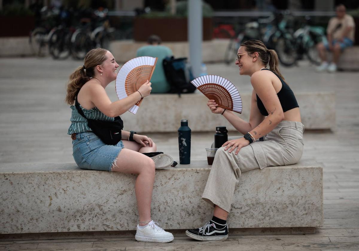 Dos jóvenes se resguardab del calor en la plaza de la Reina en Valencia, imagen de archivo.