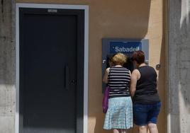 Dos mujeres sacando dinero de un cajero en una imagen de archivo.