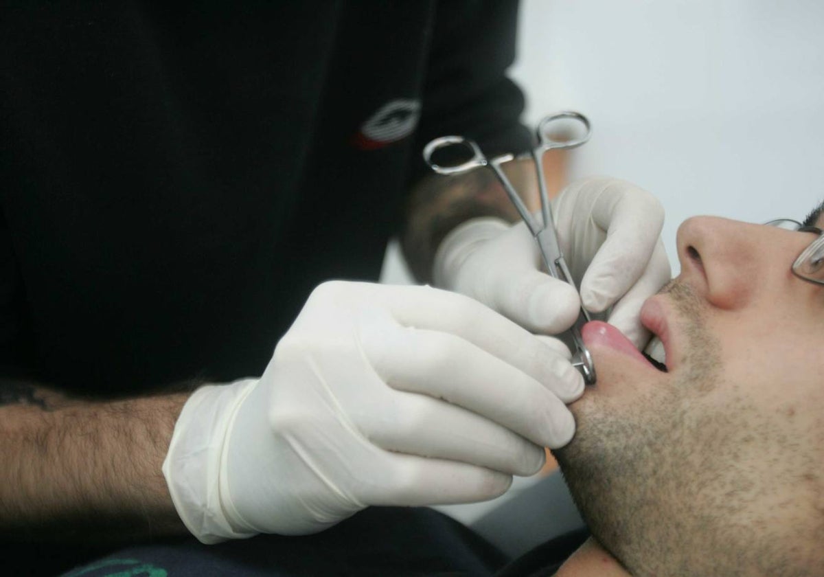 Un joven se hace un piercing en un estudio de tatuajes.