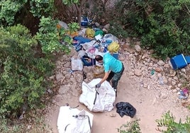 Operarios retirando basura y enseres de la cala dels Testos.