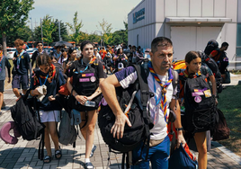 Algunos participantes del Jamboree salen del campamento con sus pertenencias.