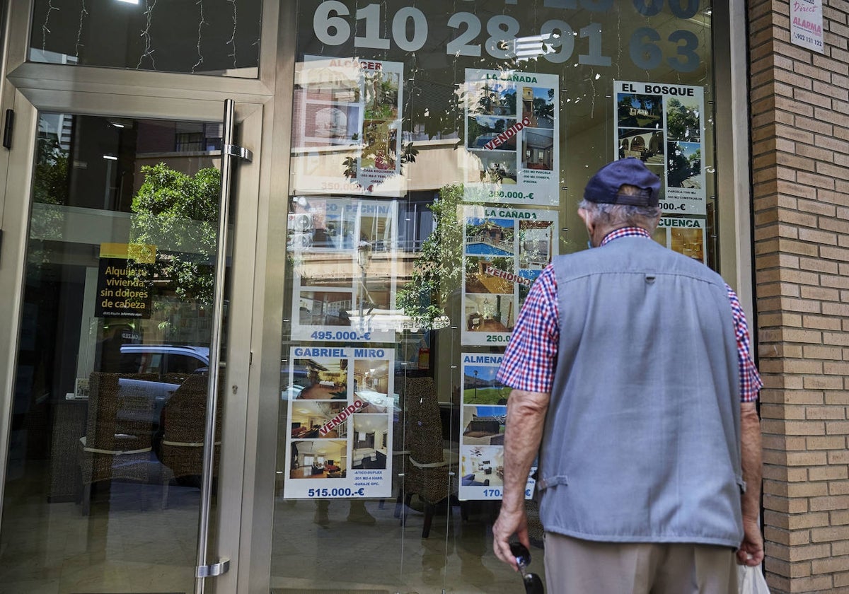 Un hombre mira carteles en una inmobiliaria.