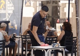 Un camarero limpia la mesa de una terraza