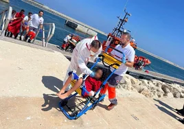 Miembros de Cruz Roja acompañan a un niño llegado en patera a la costa de Alicante.