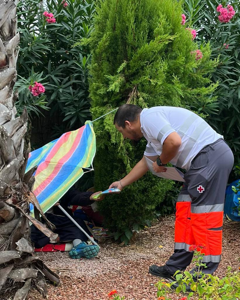 Un operario de Cruz Roja ayuda a un sin techo durante la jornada de lluvia en Alicante.