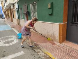 Elvira limpia la calle para retirar los restos de barro.