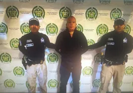 Dos policías posan con el narcotraficante detenido tras su captura en Bogotá.