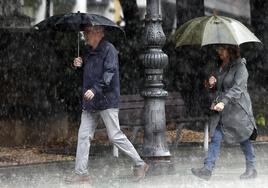 Dos personas se refugian de las fuertes lluvias en una imagen de archivo.