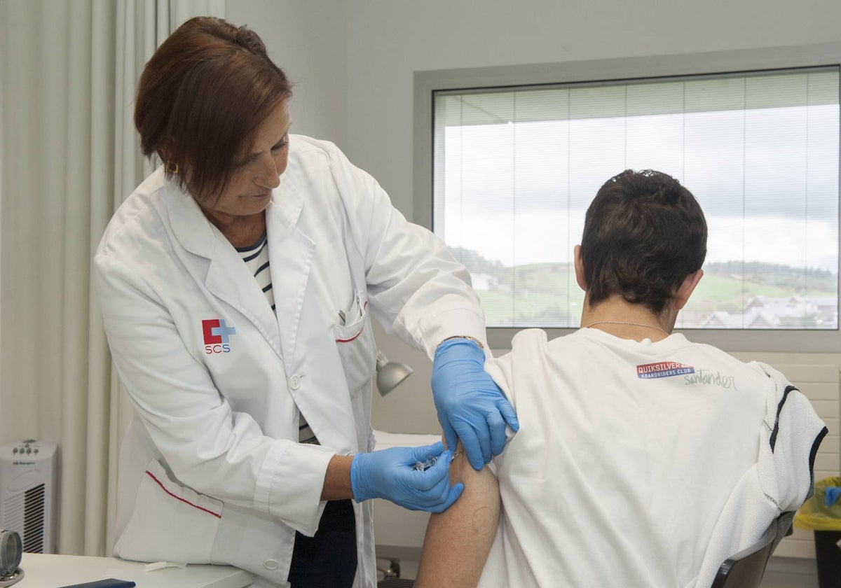 Una sanitaria vacuna a un hombre.