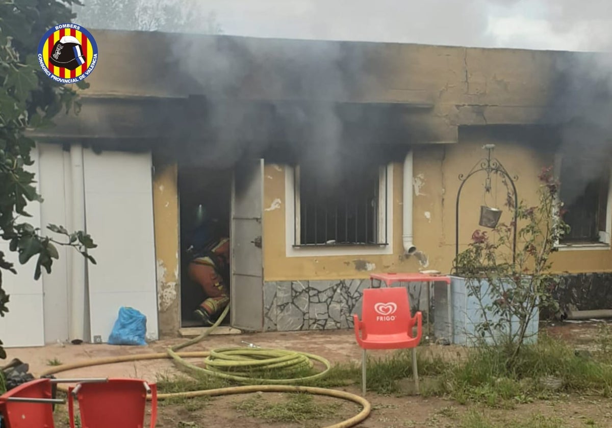 Un bombero en la entrada de la casa llena de humo tras el incendio.