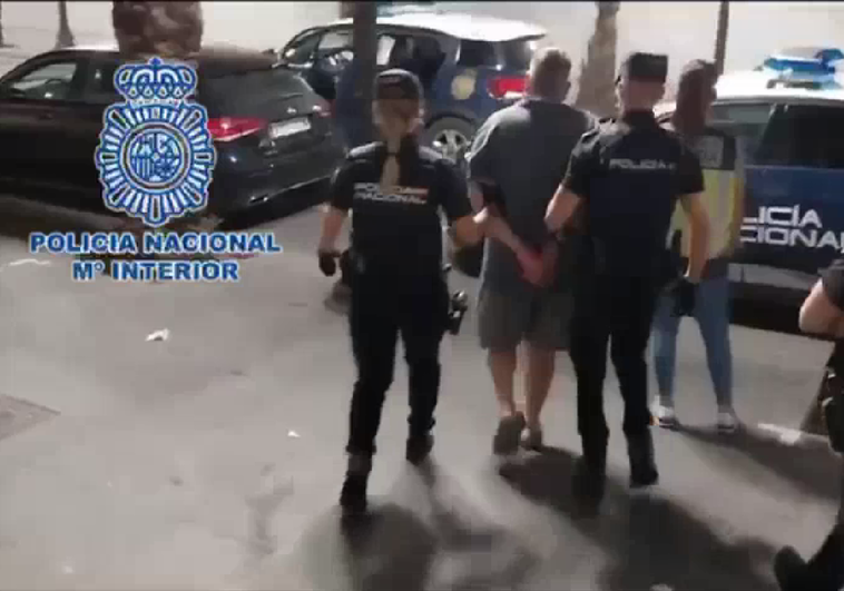 Dos policías trasladan al detenido a un coche patrulla