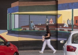 Una mujer pasa por delante del mural que reproduce el cuadro de Hopper en la esquina de Poeta Mas y Ros con Historiadora Sylvia Romeu.