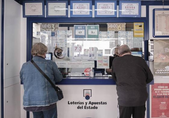 Dos personas comprando en una administración de Lotería.