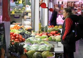 Una mujer realizando la compra de verduras en un mercado local, imagen de archivo.