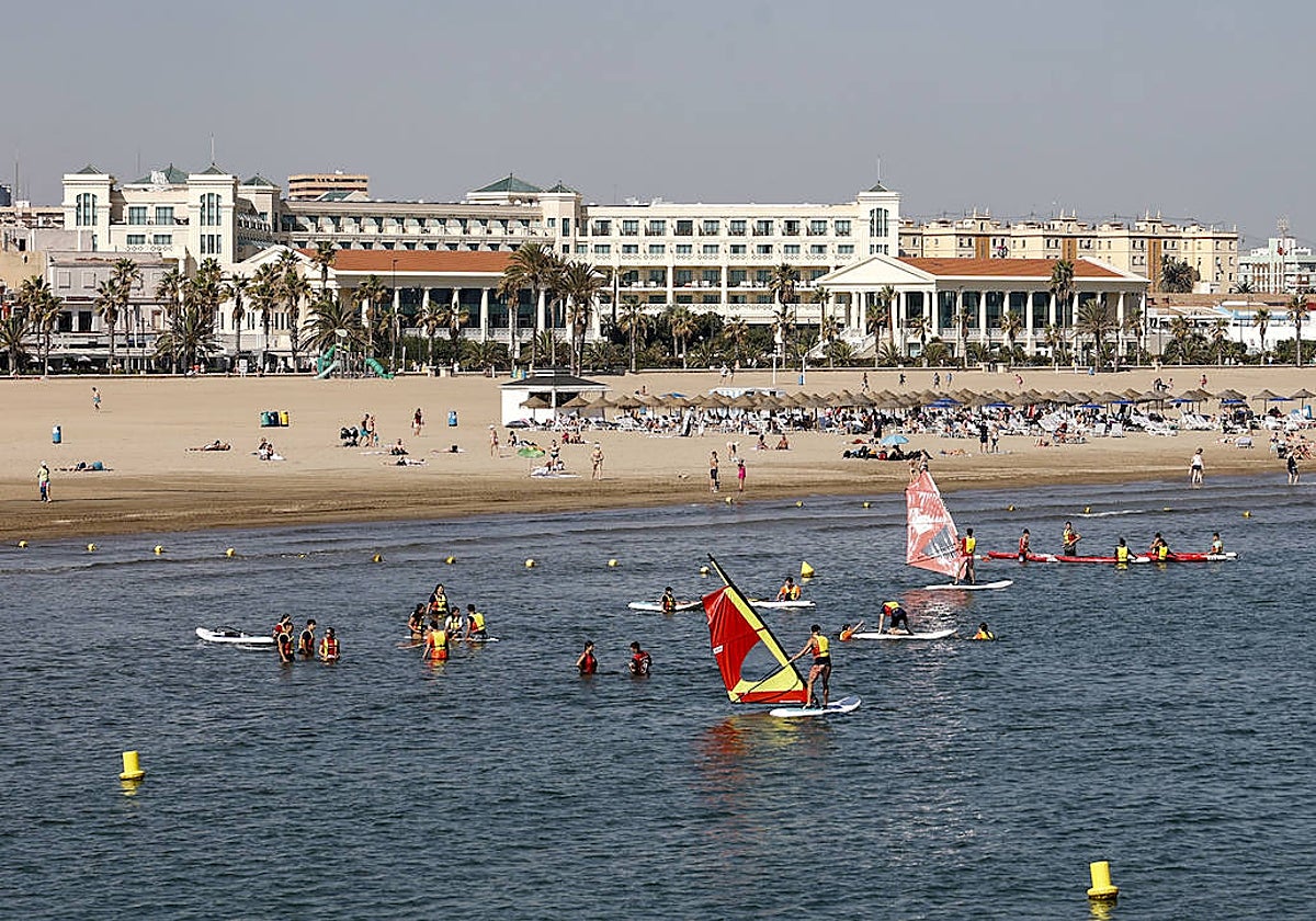 Playa de las Arenas, con bañistas y deportistas náuticos en pleno octubre.