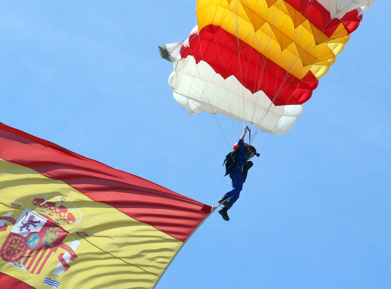 La cabo paracaidista Carmen Gómez Hurtado desciende con una bandera de España en el desfile del Día de las Fuerzas Armadas.