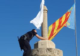 Un agente de Policía Local retira la bandera, este viernes.