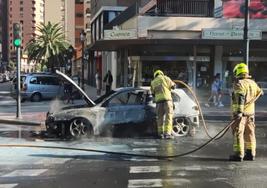 Los bomberos, durante las tareas de extinción del fuego en el vehículo.