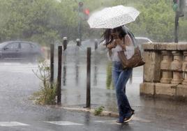 Una mujer se refugia de las fuertes lluvias intensas en la ciudad de Valencia.