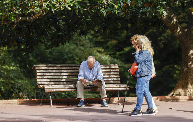 Un jubilado lee el periódico en un parque.