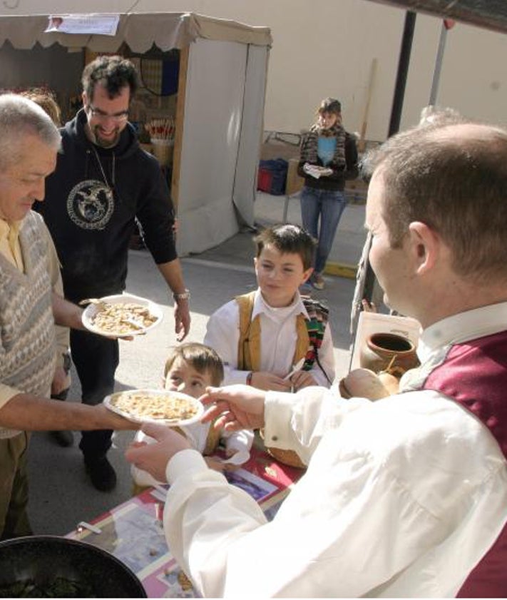 Imagen secundaria 2 - Arriba, gazpacho de pastor en la sartén que se utiliza en Quesa; sobre estas líneas fotos de archivo del reparto de los gazpachos que se elaboran y se reparten a todo el pueblo en fiestas como la de La Reserva de la localidad.