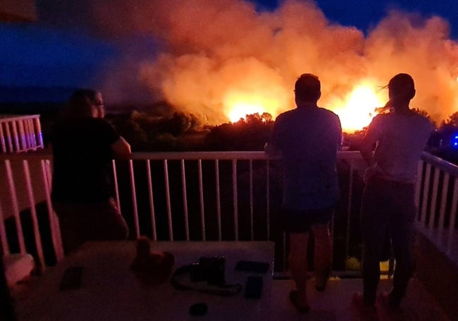 Varios vecinos observan desde su vivienda el incendio, anoche.