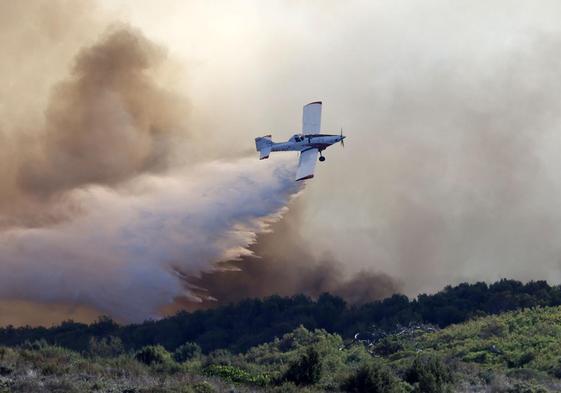 Una avioneta realiza una descarga de agua durante el incendio que afectó este sábado a El Saler.