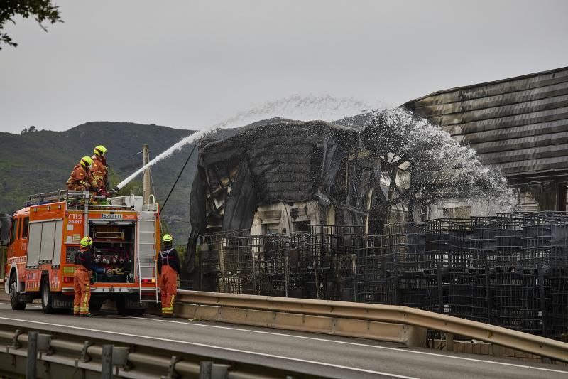 Imagen principal - Bomberos sfocando el fuego y un vehículo calcinado. IVÁN ARLANDIS