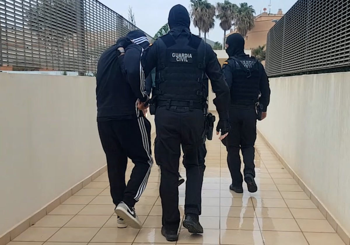 Dos guardias civiles trasladan a uno de los detenidos.