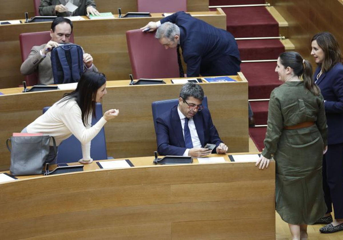 La consellera Merino habla con Mazón en Les Corts, rodeado de diputados del PP y Vox.