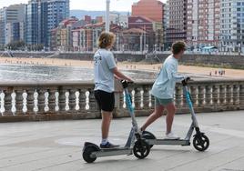 Dos jóvenes circulan en sus patinetes.