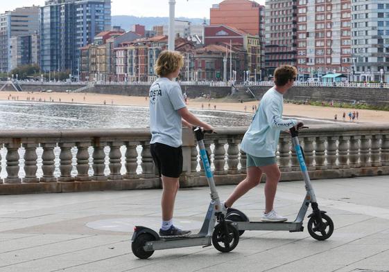 Dos jóvenes circulan en sus patinetes.