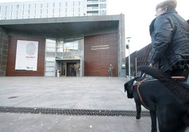 Una señora con un perro a la entrada de un hospital.