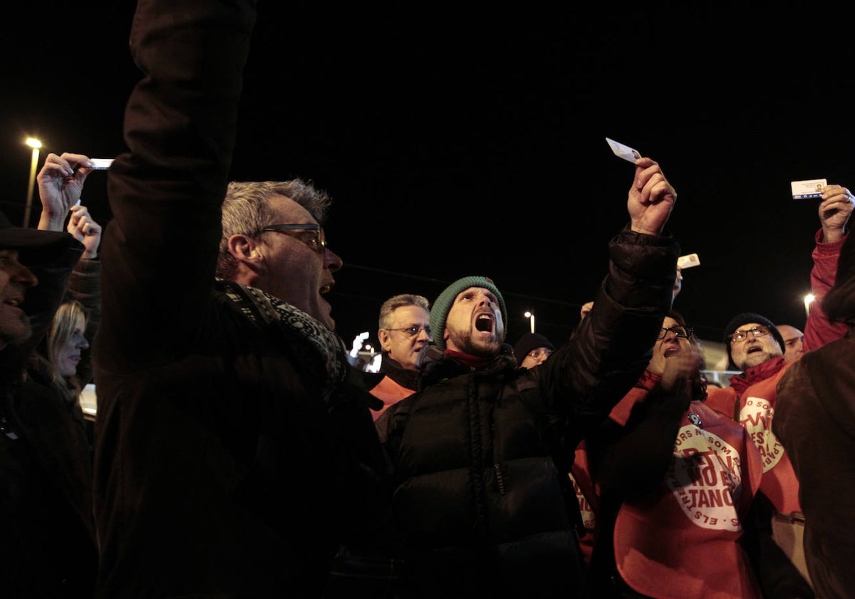 Imagen principal - Trabajadores muestran su acreditación para entrar. El momento de apertura de la verja y el reencuentro con los compañeros de turno en el interior de la sede