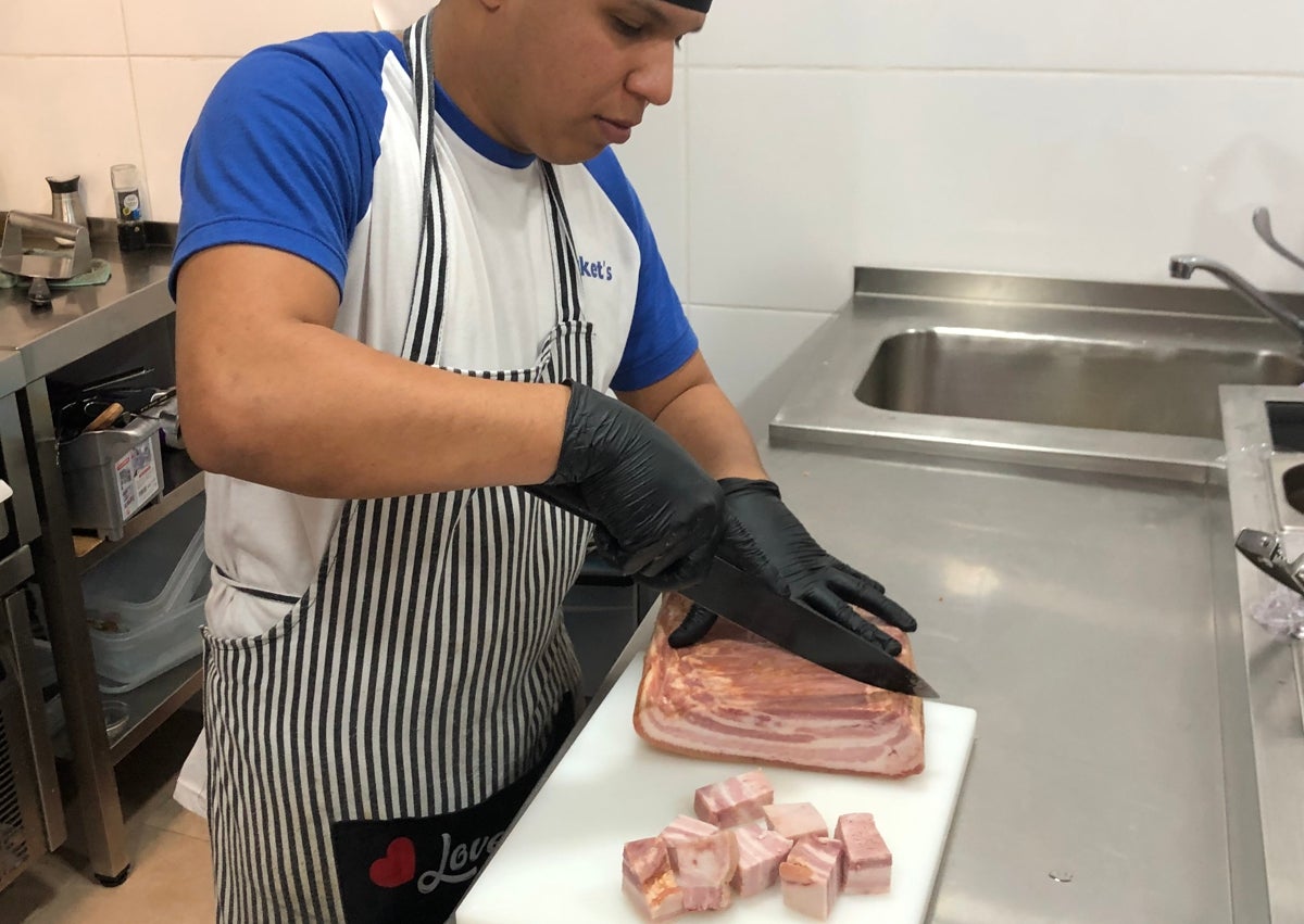 Imagen secundaria 1 - Fede Millet, impulsor del negocio, y un cocinero cortando panceta para los torreznos y preparando patatas frescas para freírlas. 