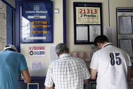 Varias personas realizan sus apuestas en una administración de Lotería.