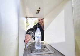 Una mujer rellena su botella en la fuente de agua refrigerada y filtrada ubicada en la Plaza del Ayuntamiento de Valencia.