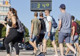 Unos turistas pasan ante un termómetro en Valencia.