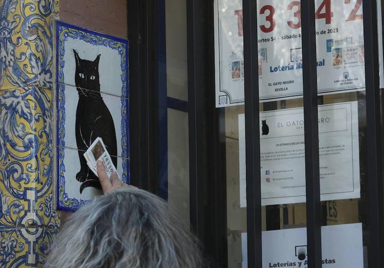 Una mujer frota un décimo recién comprado en la Administración de Loterias del Gato Negro de Sevilla.