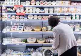 Una mujer compra queso en un supermercado.