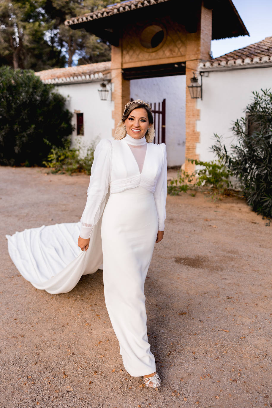 Pilar Giménez luce un vestido del atelier de Rosas Rosa con una larga capa, cuello alto y mangas con un ligero farol.