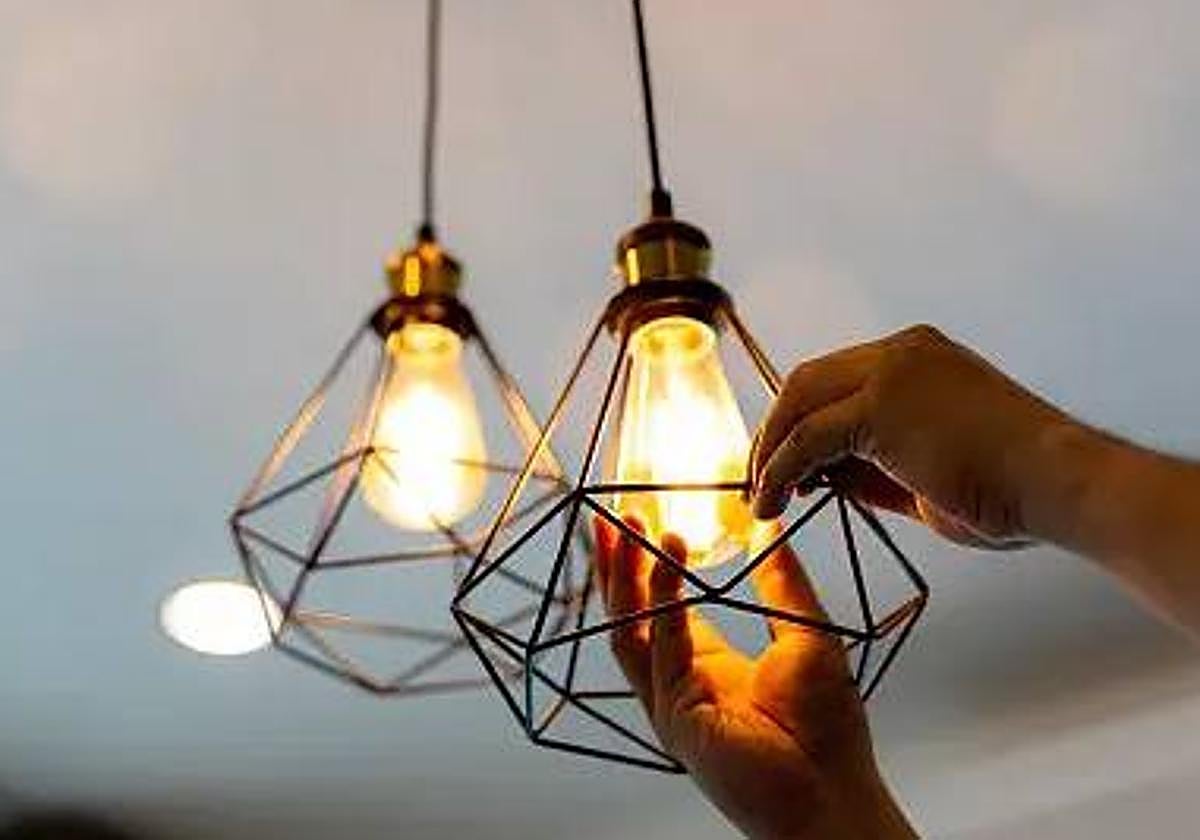 Una persona coloca una bombilla en una imagen de archivo.