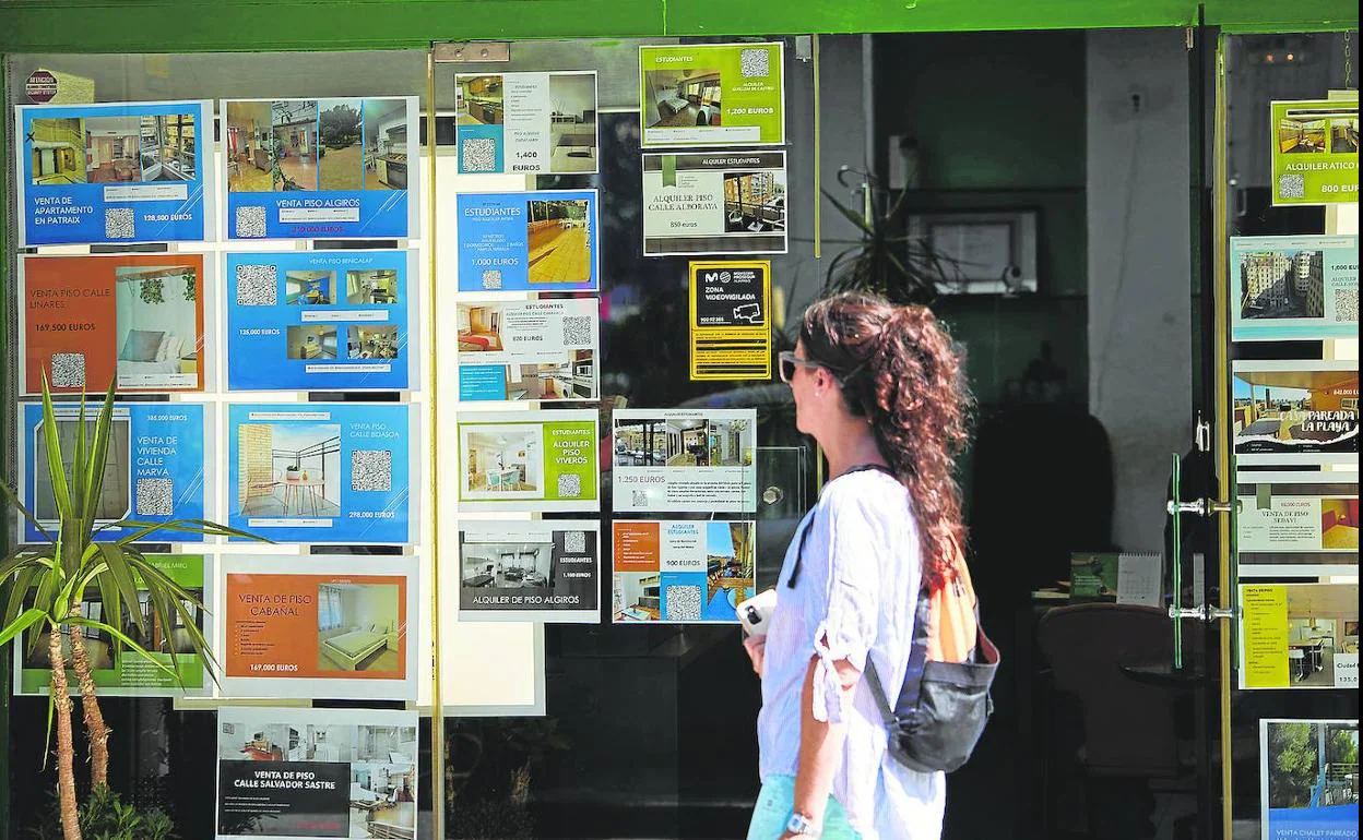 Una joven mira los anuncios de alquiler y compra de una inmobiliaria en Valencia. 
