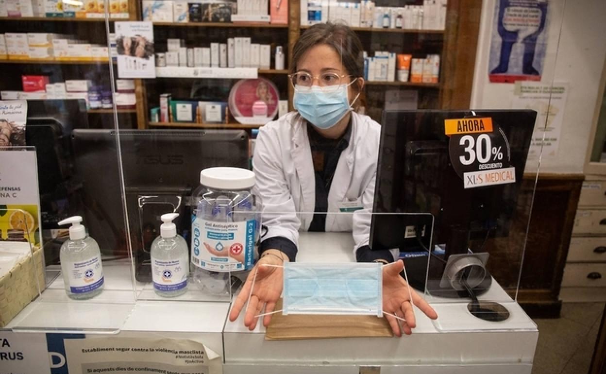 Una farmacéutica muestra una mascarilla durante la pandemia