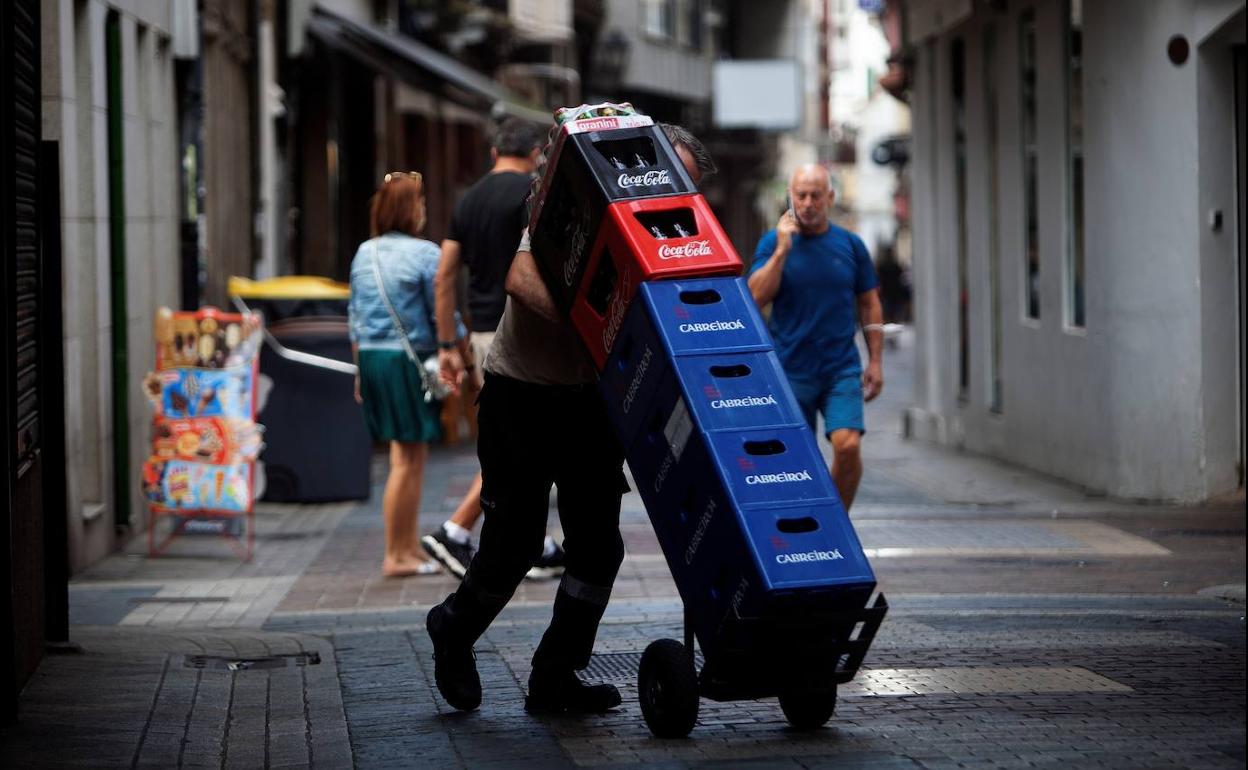 Un repartidor carga con cajas de bebidas.