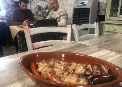 Imagen secundaria 1 - Juan Benavent frente a las brasas, una 'torrrà' y una camarera con medio bocadillo. 