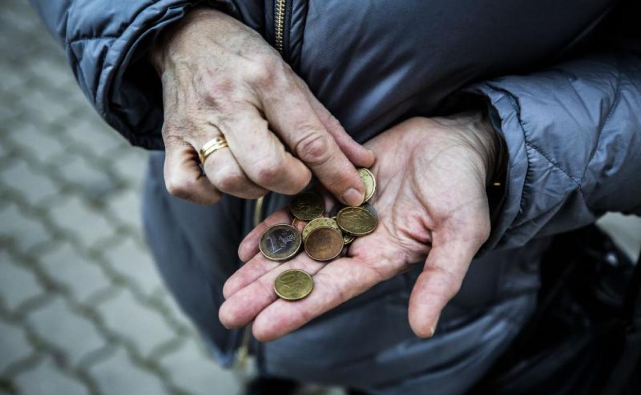 Un pensionista cuenta el dinero que tiene en la mano.