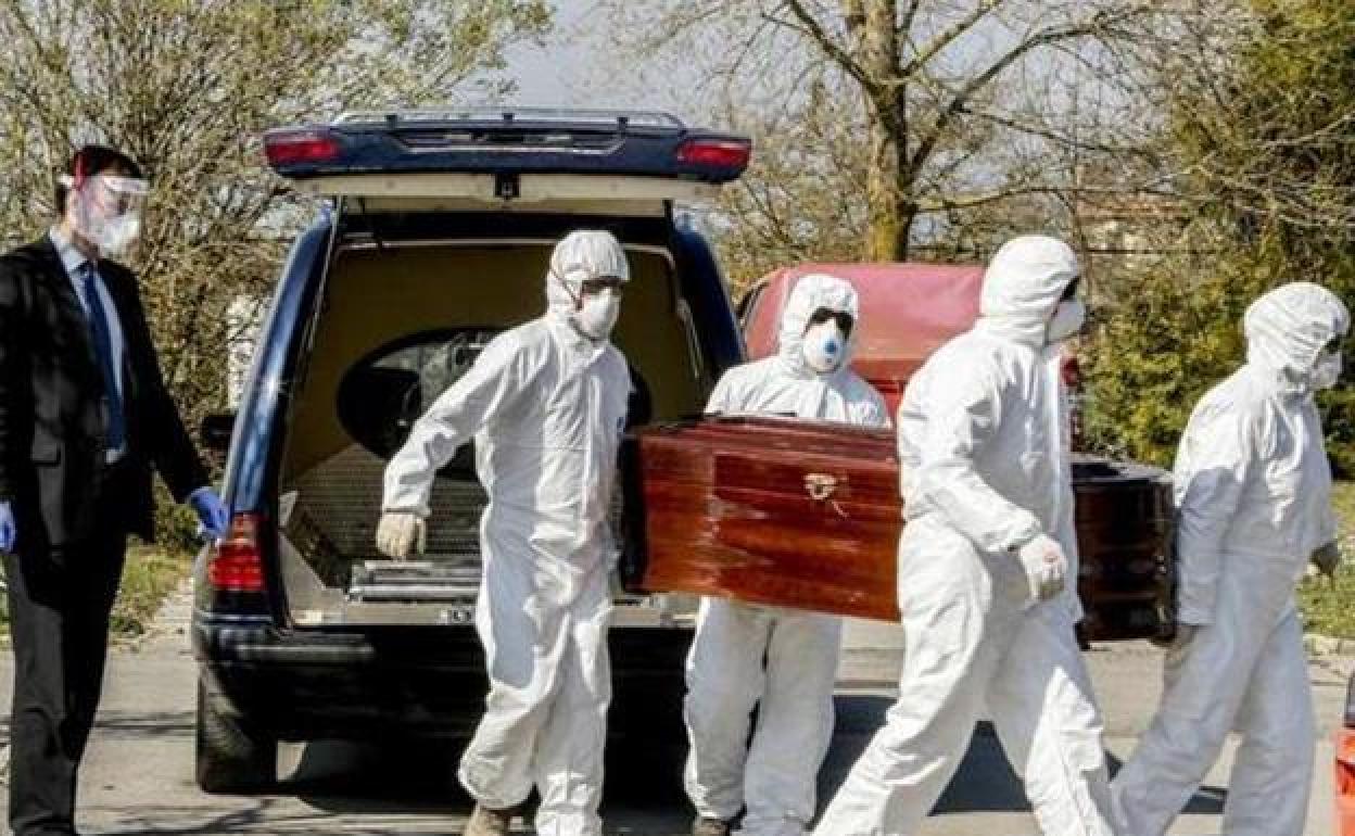 Trabajadores de una funeraria portan el cadáver de un fallecido por covid.