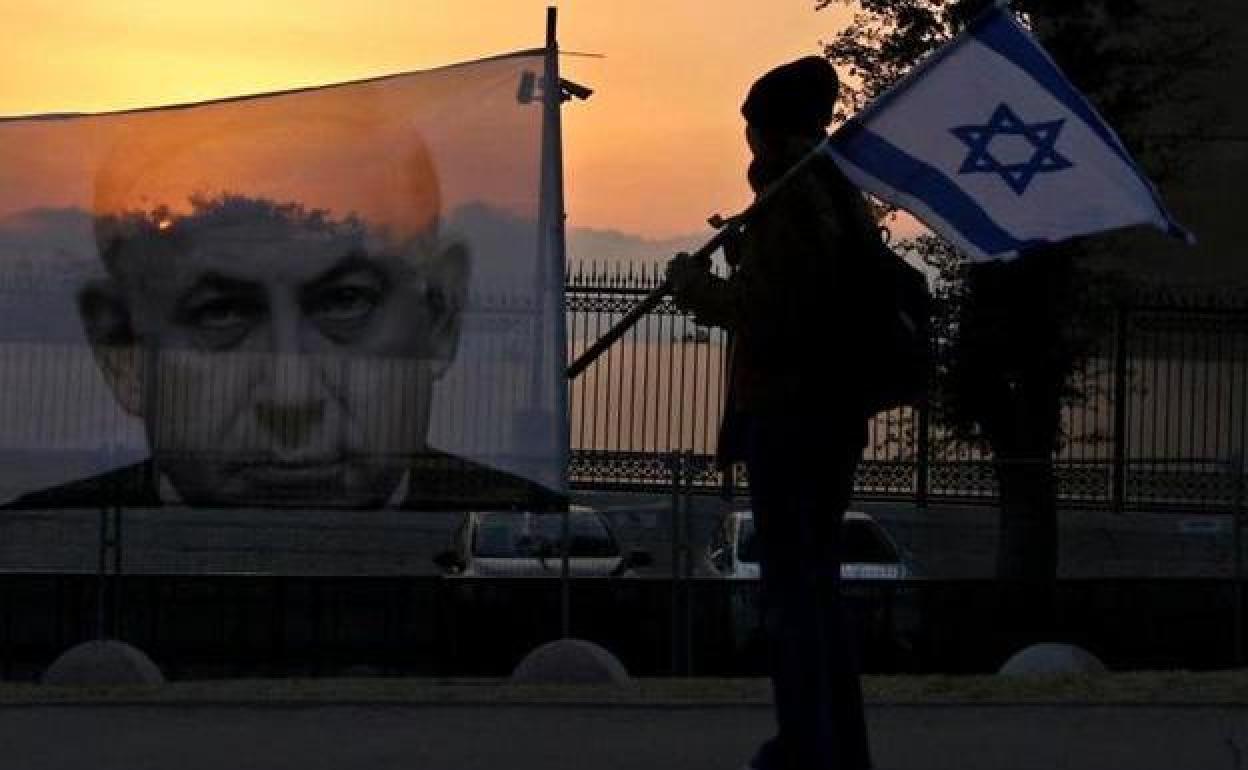 Un manifestante camina frente a un retrato del primer ministro israelí, Benyamin Netanyahu, en una calle de Jerusalén